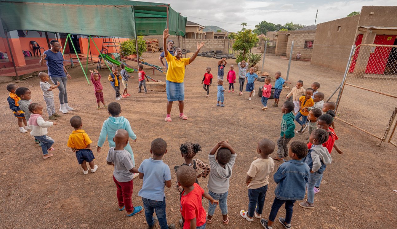 Children playing a movement game in a circle with a facilitator